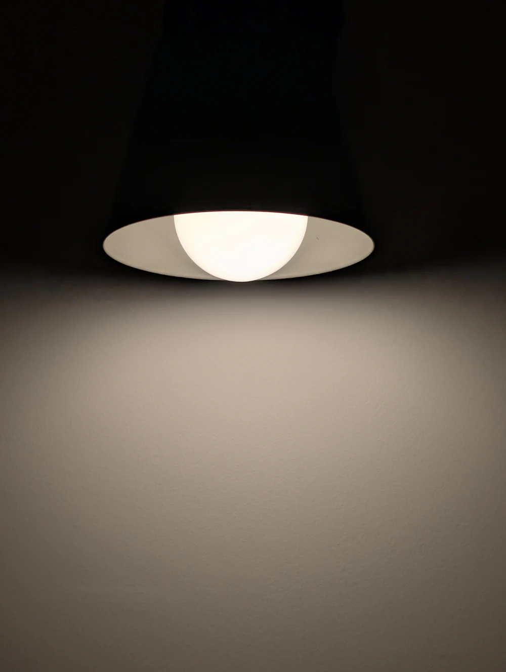 Suspension lumineuse éclairant un mur dans la pénombre